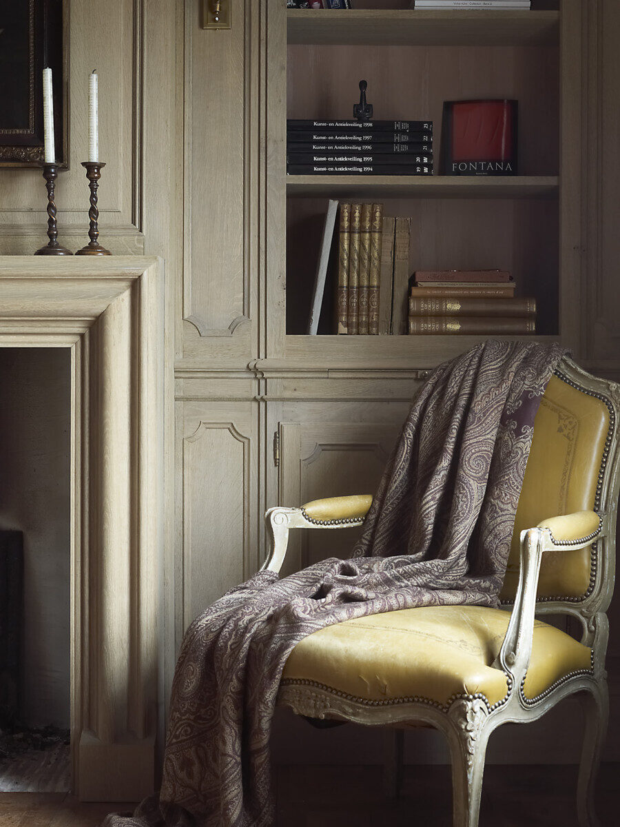 Een interieur project op maat. Toont een stoel en een muur met wood panelling en bibliotheek